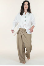 camisa blanca de botones con esmeraldas verdes y pantalón tostado con broche dorado
