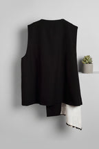 Chaleco asimétrico en negro con estampado latera beige cerrado con botones LYKKE